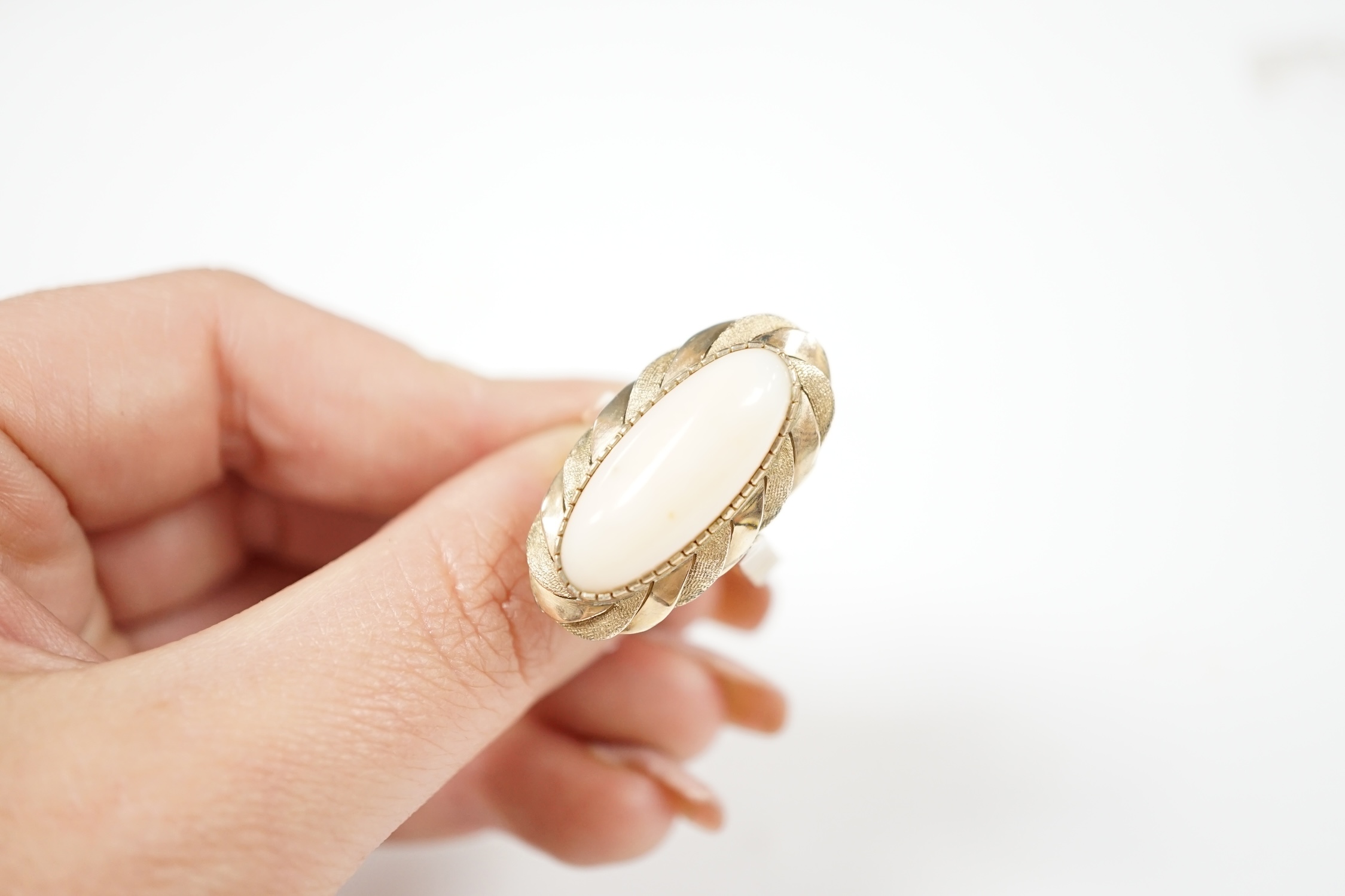 A yellow metal and single stone cabochon white coral set oval ring, size Q, gross weight 7.6 grams.